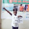 Girl with sign saying "Clean up the Niger Delta now"